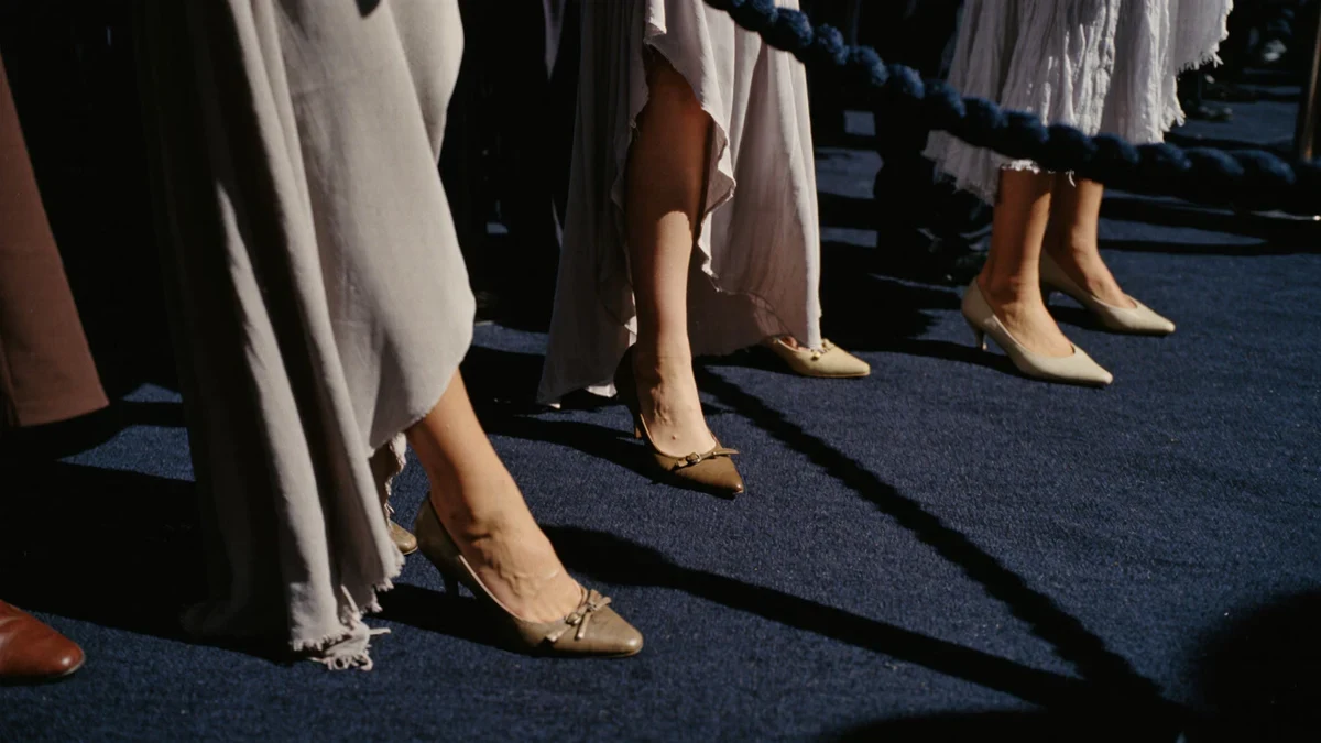 Velvet ropes line a museum courtyard as flash bulbs ripple across a Gucci-dark carpet of tailored silhouettes.