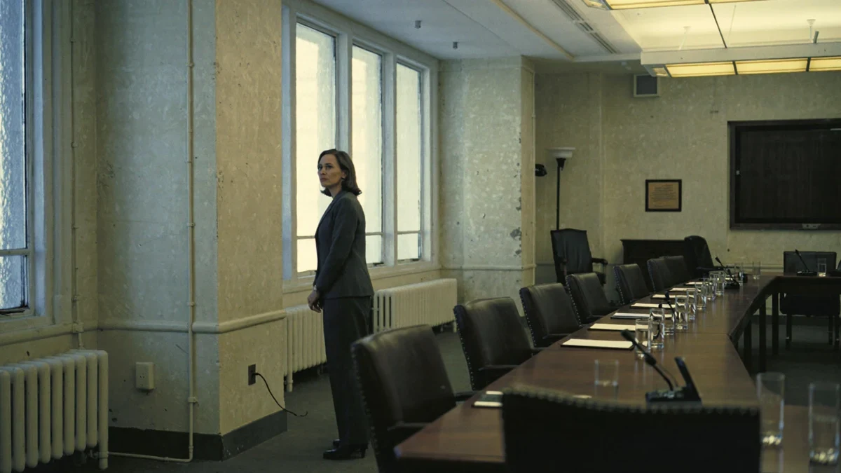 A long acquisition conference table with contract binders and a drafting lamp in an orderly federal office.